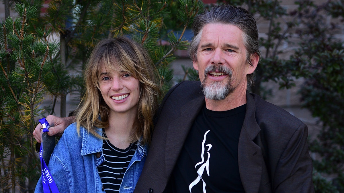 Ethan Hawke and Maya Hawke smiling at a film premiere.