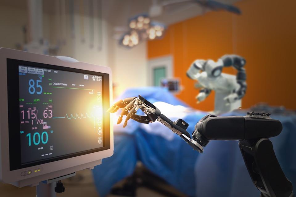 Robot hand reaching for medical readout screen.