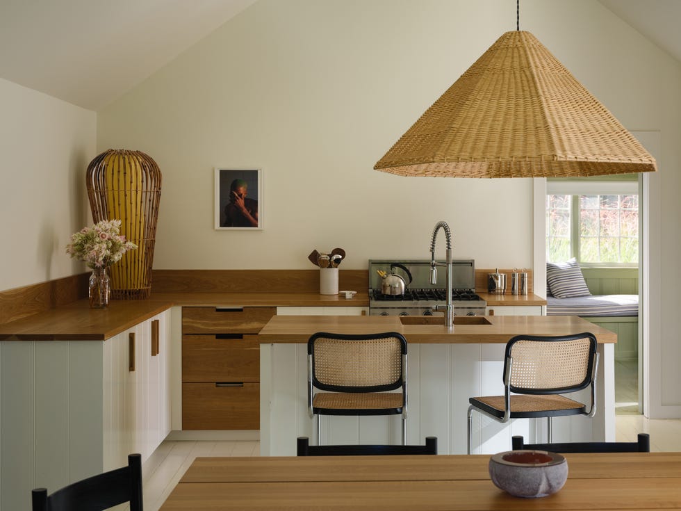 Modern kitchen with wicker pendant light, wooden countertops, and bar stools.