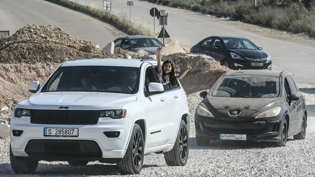 A girl flashes the V-sign from a vehicle as displaced residents cross the Bourj Rahal bridge on their way to their village in southern Lebanon .