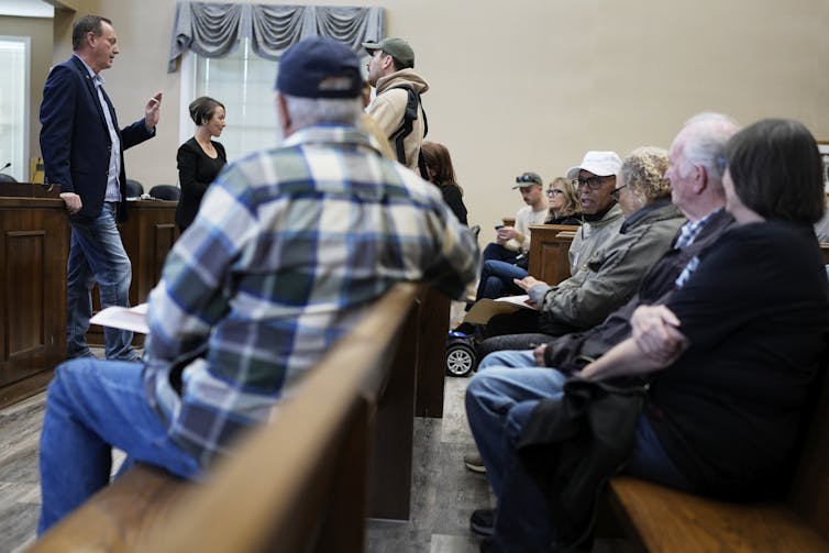 People engage at a meeting, where many of them appear to be over 65.