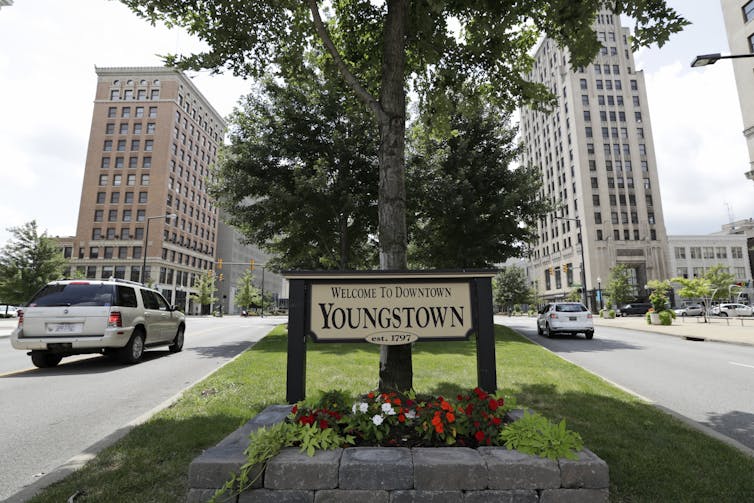 A sign in front of trees and flowers reads 'Welcome to Youngstown.'