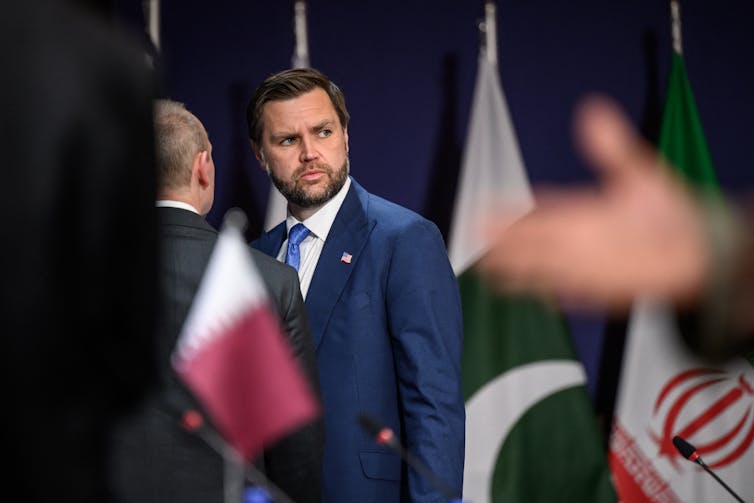 A man in suit and tie turns and looks backward.