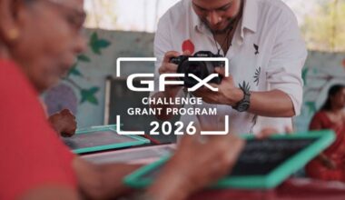 A photographer takes pictures of people writing on small chalkboards, with the text “GFX Challenge Grant Program 2026” overlaid in the center of the image.