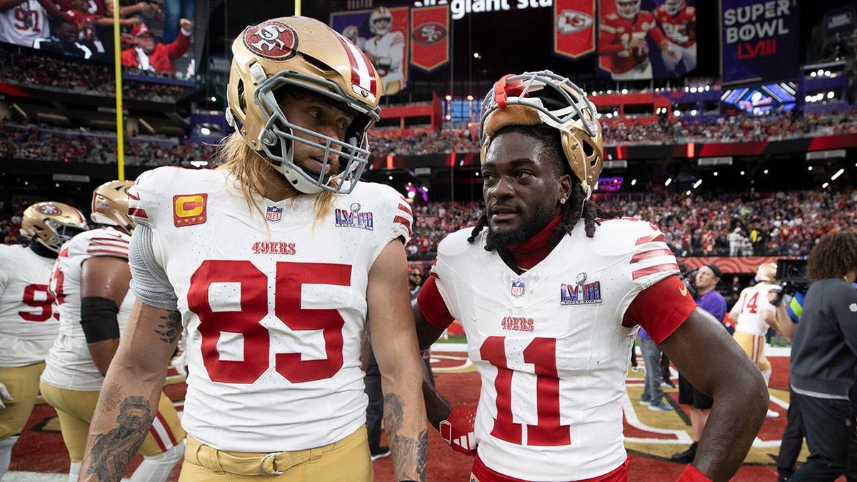 George Kittle and Brandon Aiyuk standing on the field at Allegiant Stadium in Las Vegas.
