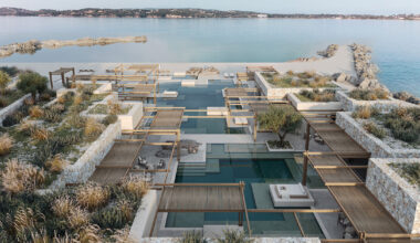 beach club’s stepped stone volumes surround lagoon-like pool in greece