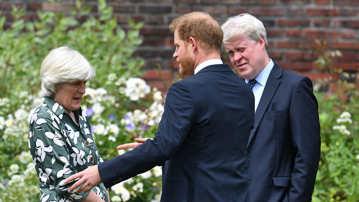 Prince Harry standing with his aunt Lady Jane Fellowes and uncle Earl Spencer in a garden at Kensington Palace