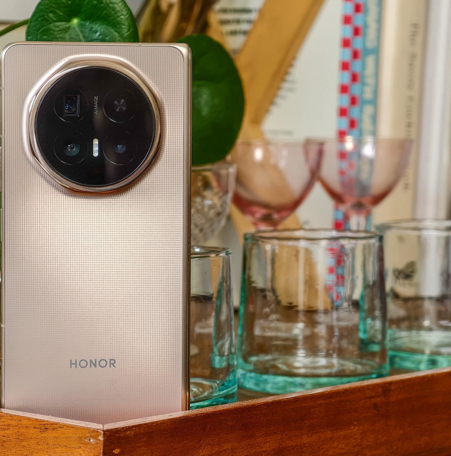 Photo of Honor Magic V6 on a wooden trolley with a pot plant and glassware, closed and showing the rear