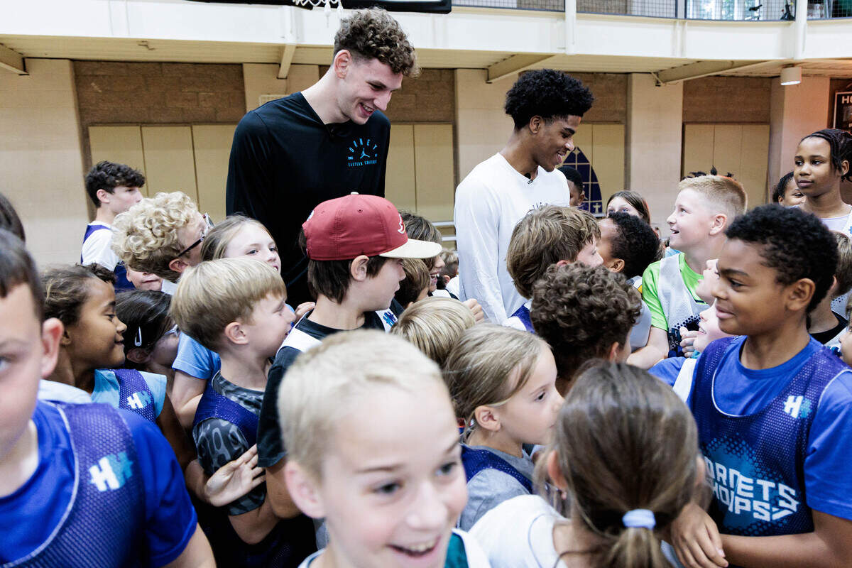 Hornets Hoops campers swarm Charlotte Hornets first-round draft picks Hannes Steinbach (left) and Christian Anderson Jr. before taking a group photo on Wednesday, June 24, 2026 at Covenant Presbyterian Church.