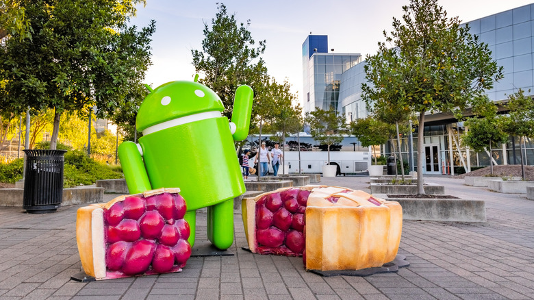 Android bot mascot with open pies out front of headquarters.