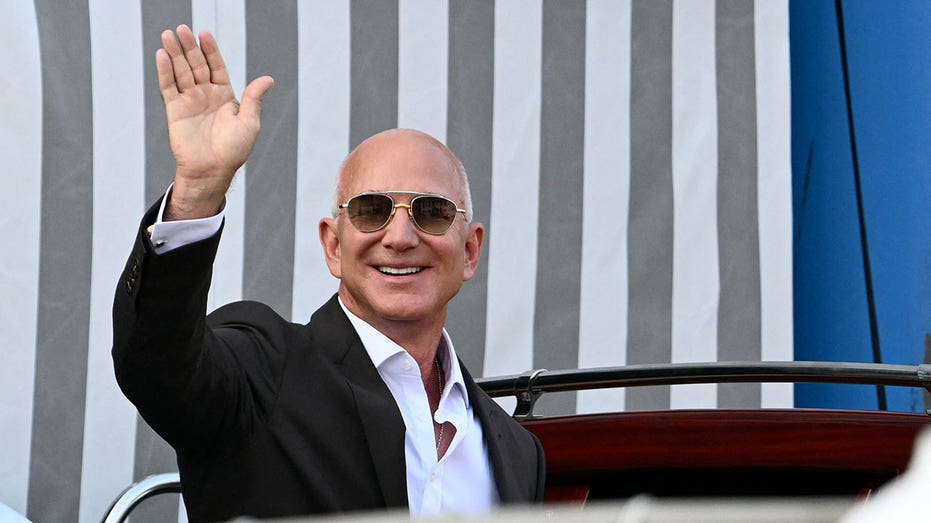 Amazon's founder Jeff Bezos waves as he gets on a taxi boat at the Aman Hotel in Venice on June 26, 2026. Celebrities in superyachts sail into Venice this week for the three-day wedding party of Amazon tycoon Jeff Bezos and Lauren Sanchez, despite irate locals who say the UNESCO city is no billionaire's playground. The tech magnate and journalist have reportedly invited about 200 guests to their multi-million dollar nuptials in the Italian city, which are expected to kick off on June 26 and end Saturday with a ceremony at a secret location. (Photo by Stefano Rellandini / AFP) (Photo by STEFANO RELLANDINI/AFP via Getty Images)