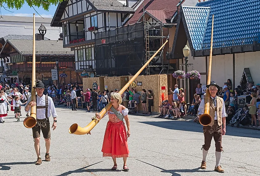 People dressed in traditional German clothes carry large alpenhorns during the Maifest celebration in Leavenworth, Washington