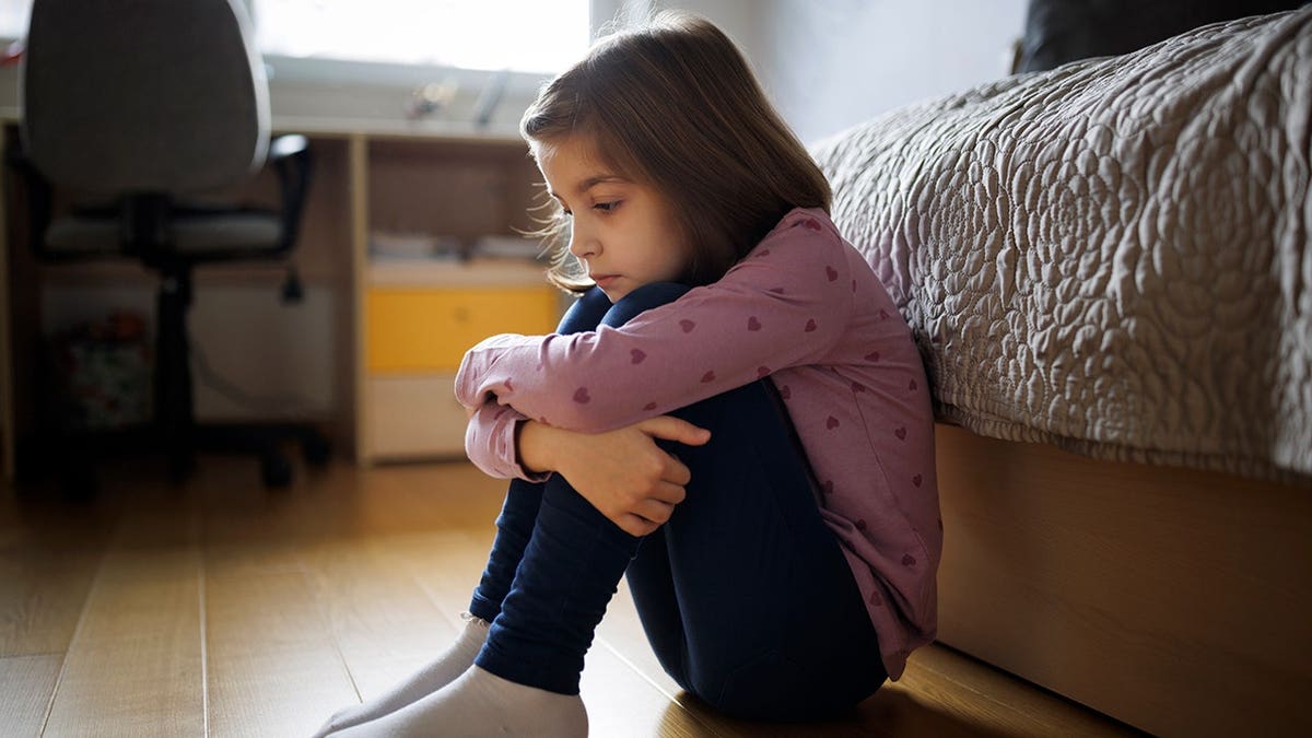 Little girl sitting alone on the floor at home