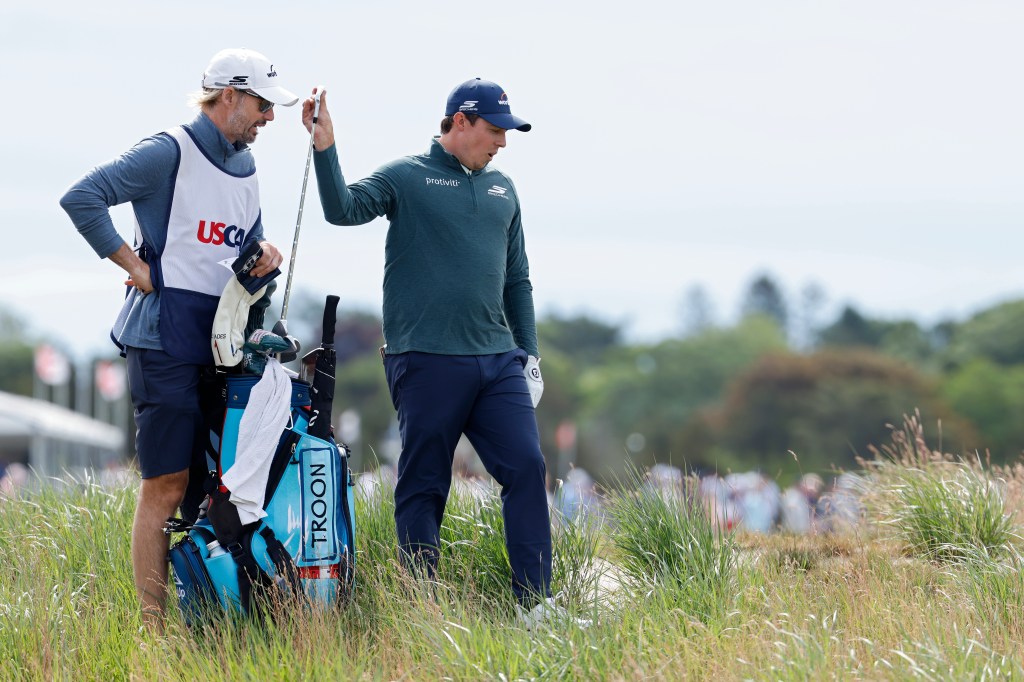 Golfer Matt Fitzpatrick and his caddie discuss club selection on the sixth hole during the 126th U.S. Open.
