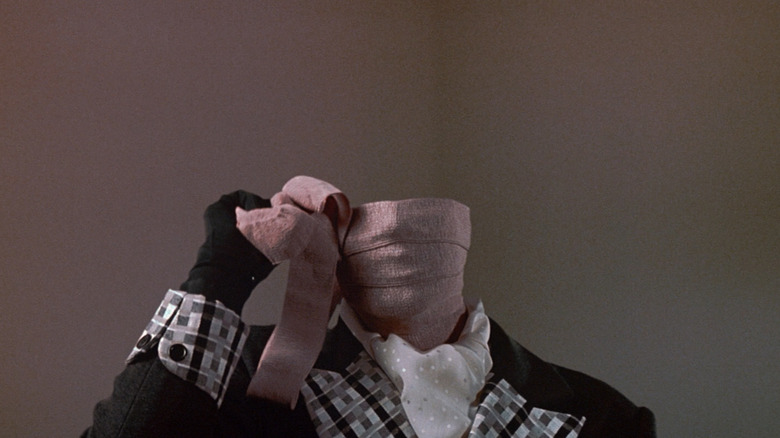 Chevy Chase as Nick Halloway unwraps bandages around his face in Memoirs of an Invisible Man
