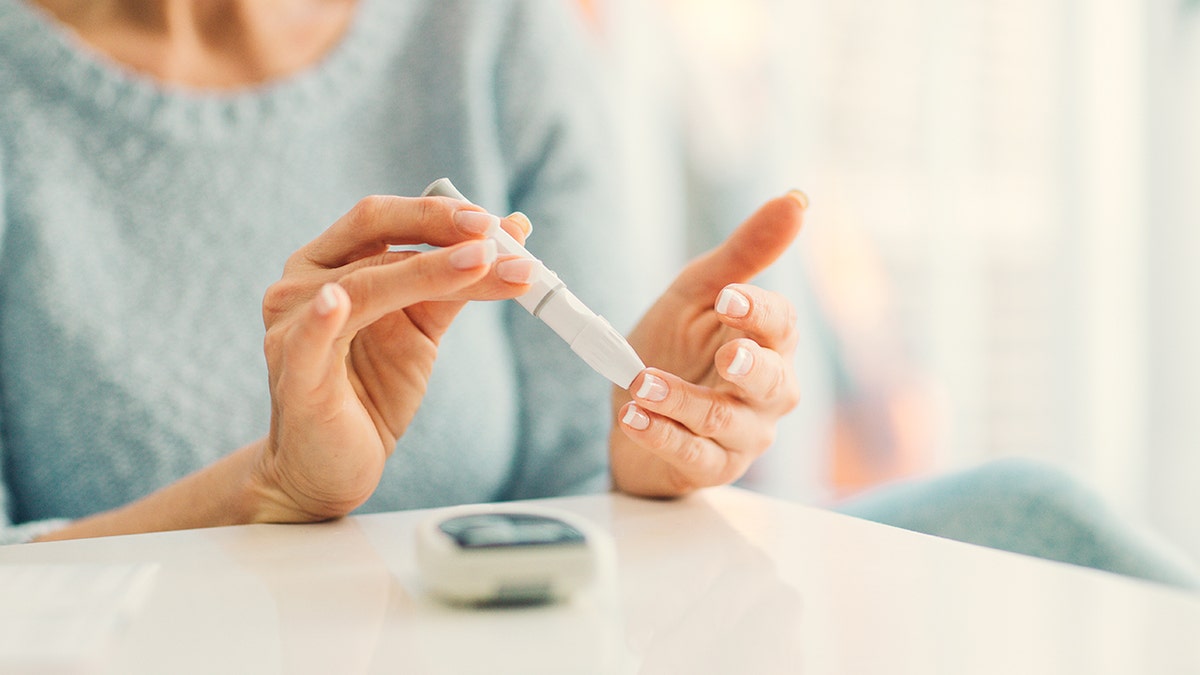Diabetic woman checking blood sugar with finger prick.