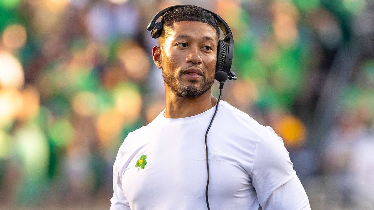 Notre Dame head football coach Marcus Freeman adjusting his radio on the sideline at Notre Dame Stadium