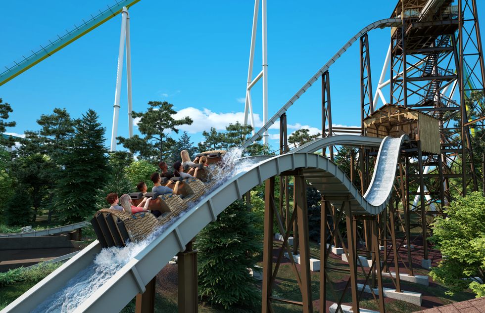 People riding a water roller coaster through a forested area under a clear blue sky at Carowinds