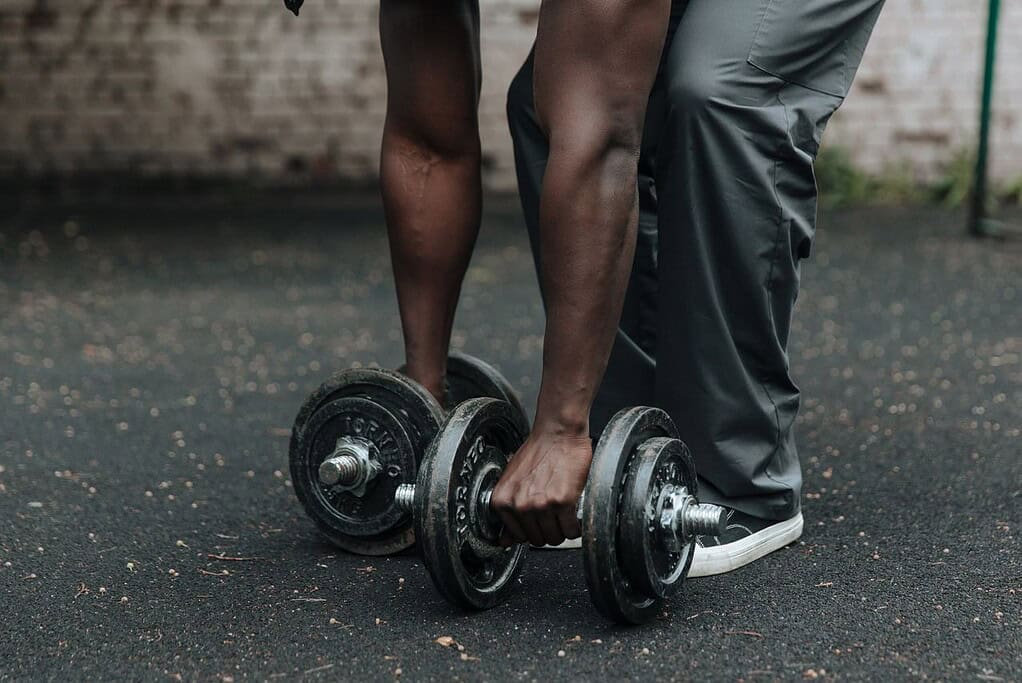 Individual lifting dumbbell during workout at outdoor gym.