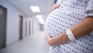 Mid section of pregnant woman standing in corridor of hospital