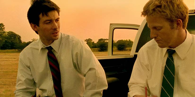 Two men on the back of a truck talking in Primer