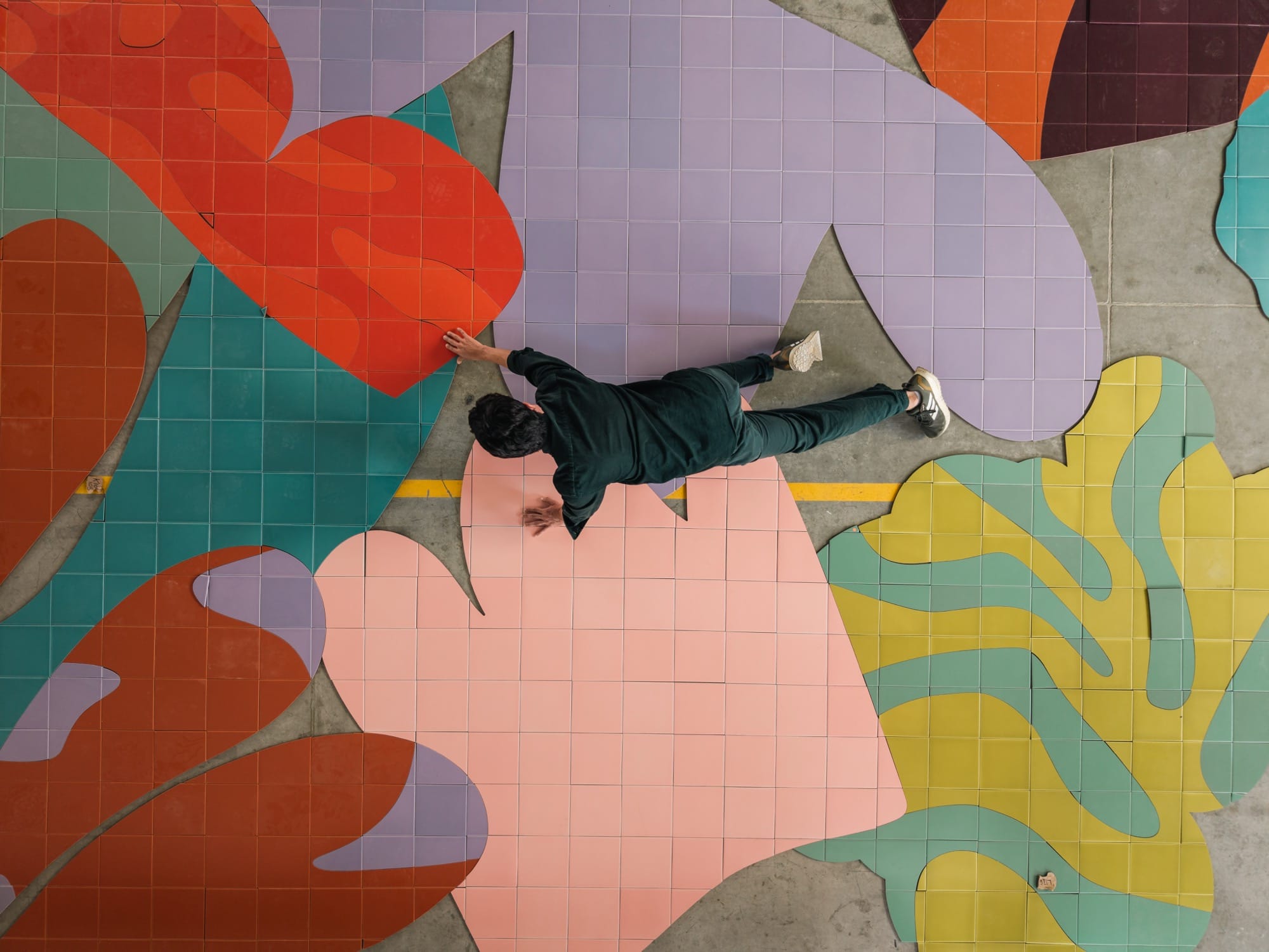 a person crawls atop colorful ceramic tiles on a floor