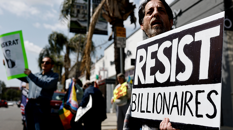 Person holding up 'resist billionaires' sign