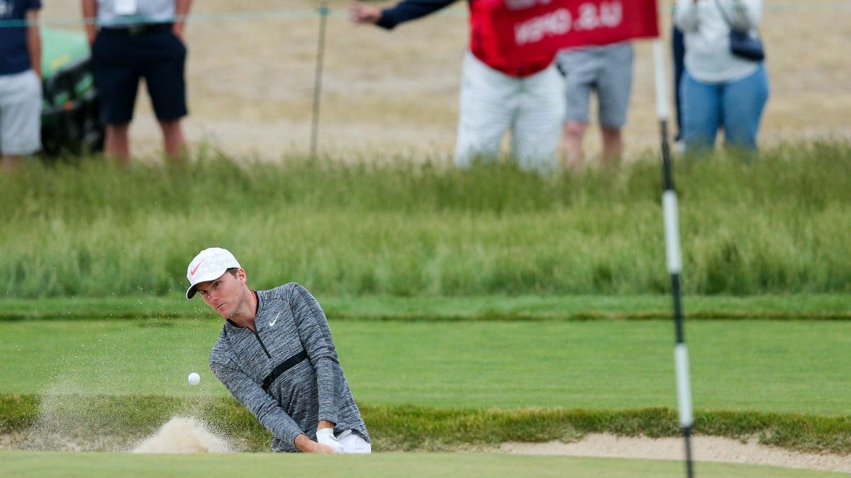 Russell Henley hitting out of a bunker onto the sixteenth green at Shinnecock Hills Golf Club