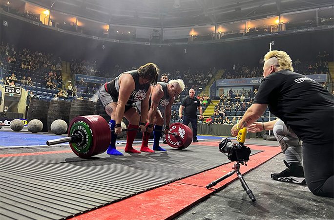 Sam doing a deadlift with Izzy as Sue cheers them on