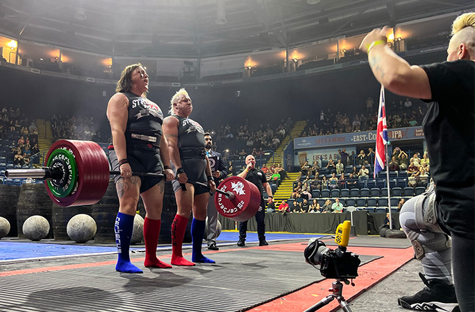 Sam doing a deadlift with Izzy as Sue cheers them on
