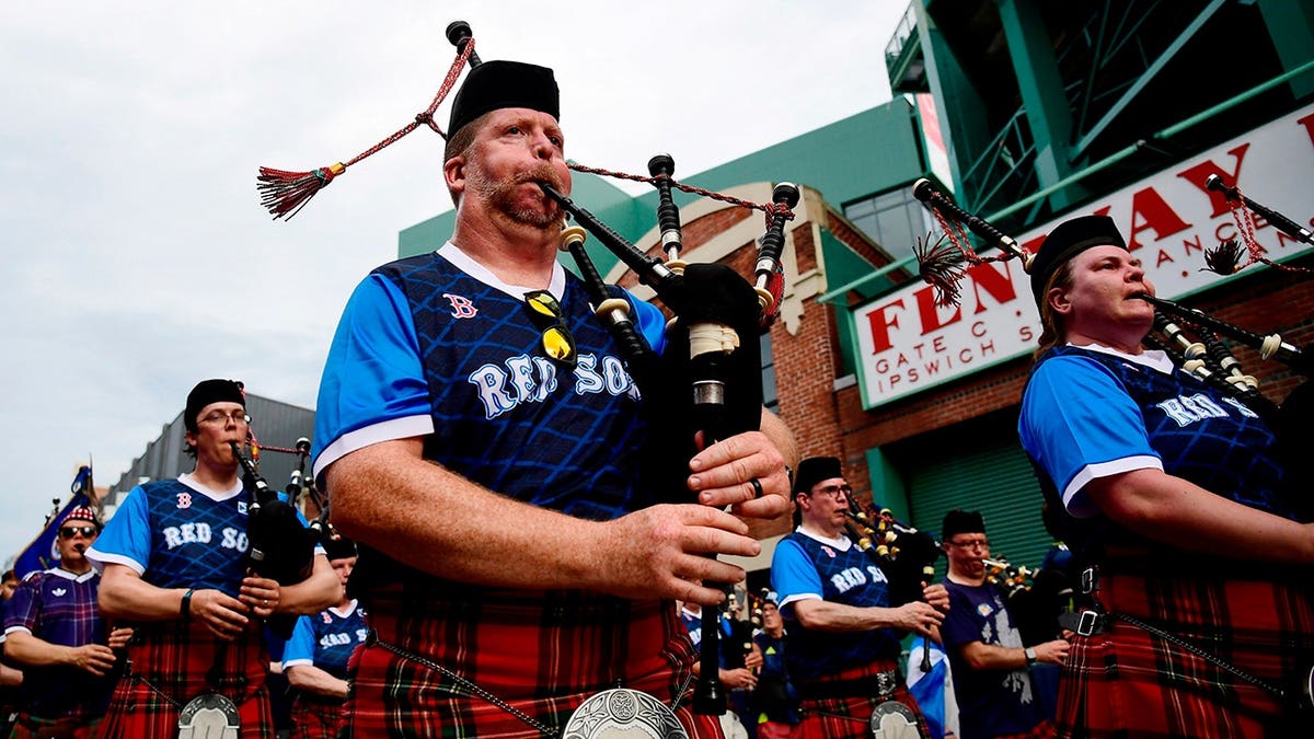 Scotland fans wearing kilts and playing bagpipes during march to Fenway Park in Massachusetts