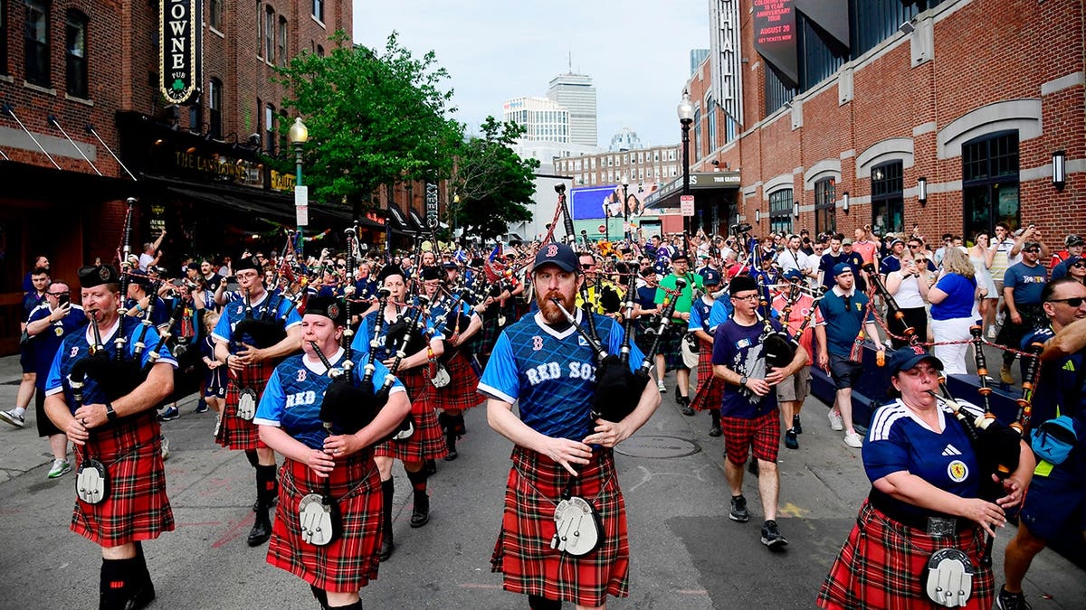 Scotland fans wearing kilts and playing bagpipes marching to Fenway Park in Massachusetts