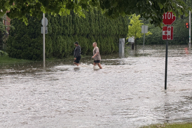Two men cross a flooded street after a storm.