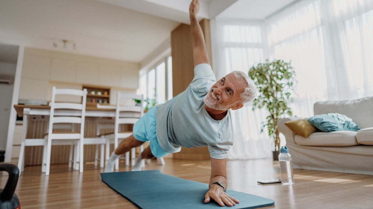 Senior man exercising at home in a living room