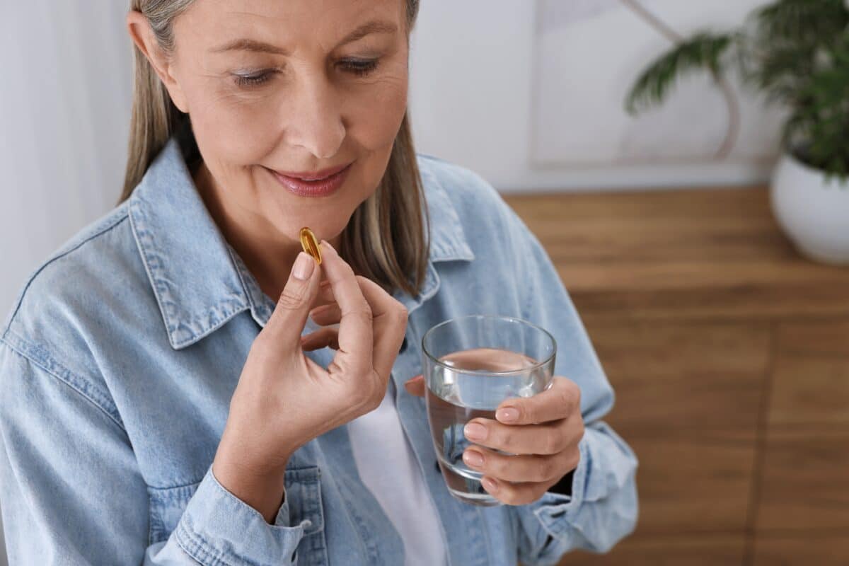 An older woman taking a supplement with a glass of water