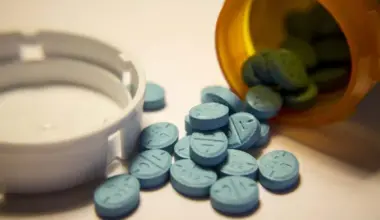 Close up of blue Adderall pills spilling out of a pill bottle, representing the Adderall shortage.