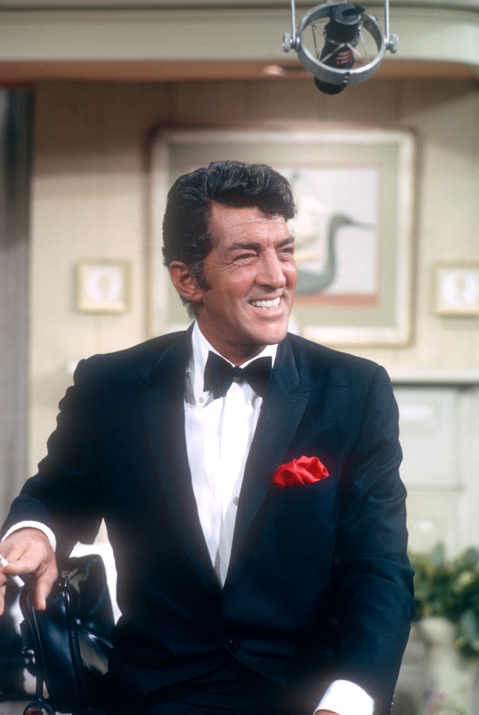Dean Martin sitting on the set of 'The Dean Martin Show' with a microphone above him.