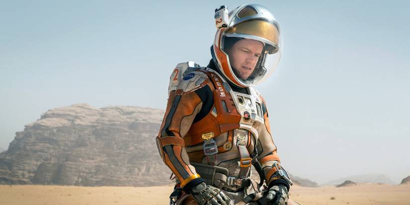 Mark Watney wearing his spacesuit and kneeling on Mars' dusty surface in The Martian