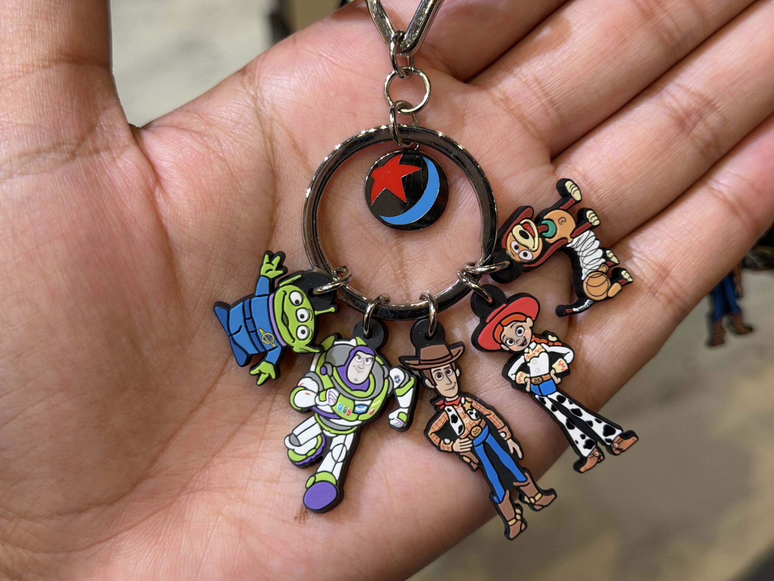 This keychain features five characters from the Toy Story franchise: a green alien, Buzz Lightyear, Jessie, and Slinky Dog. The Luxo Ball is featured too, hanging from the center ring.