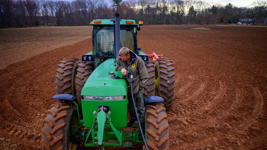 worker fuels field tractor