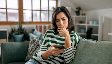 Thinking person with hand on chin looking at smartphone.