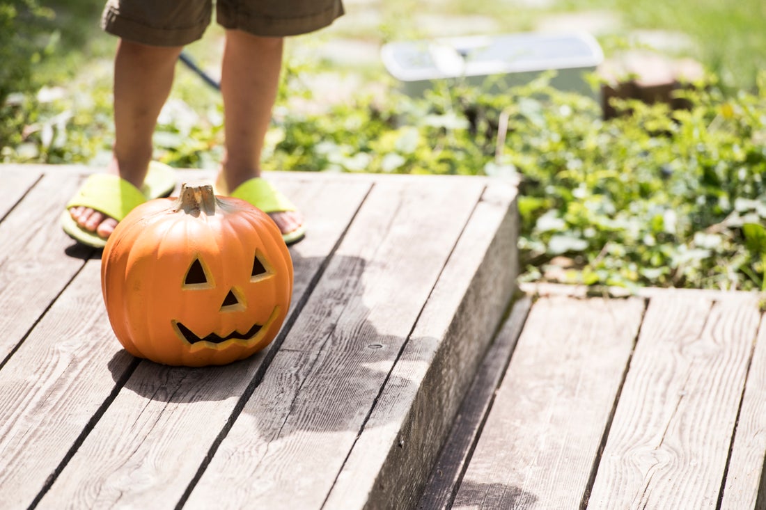 A jack-o'-lantern sitting on a wooden porch.