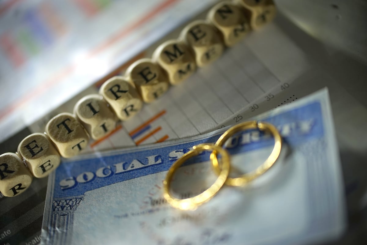 Two wedding rings lie on a Social Security card beside a string of beads that spells "retirement."