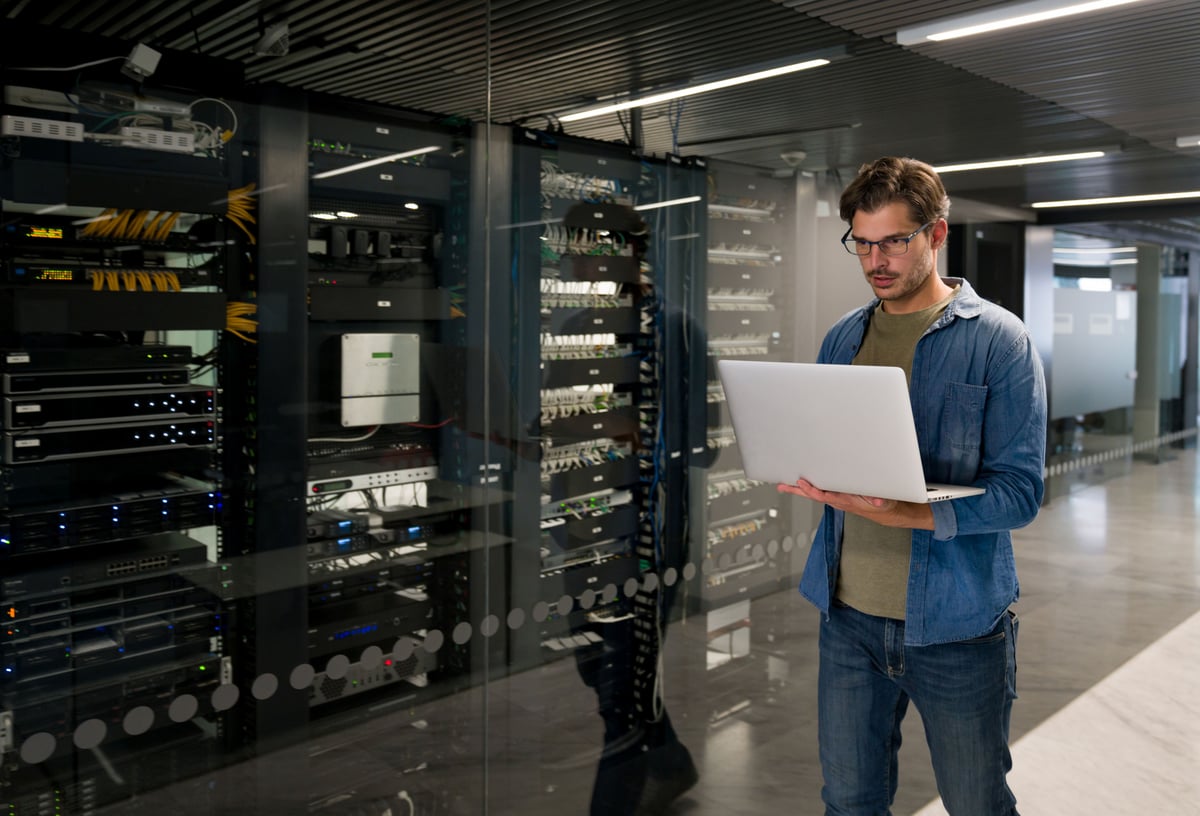 A data center technician is standing in front of a server rack.