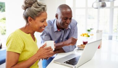 Two people looking at laptop together in kitchen.