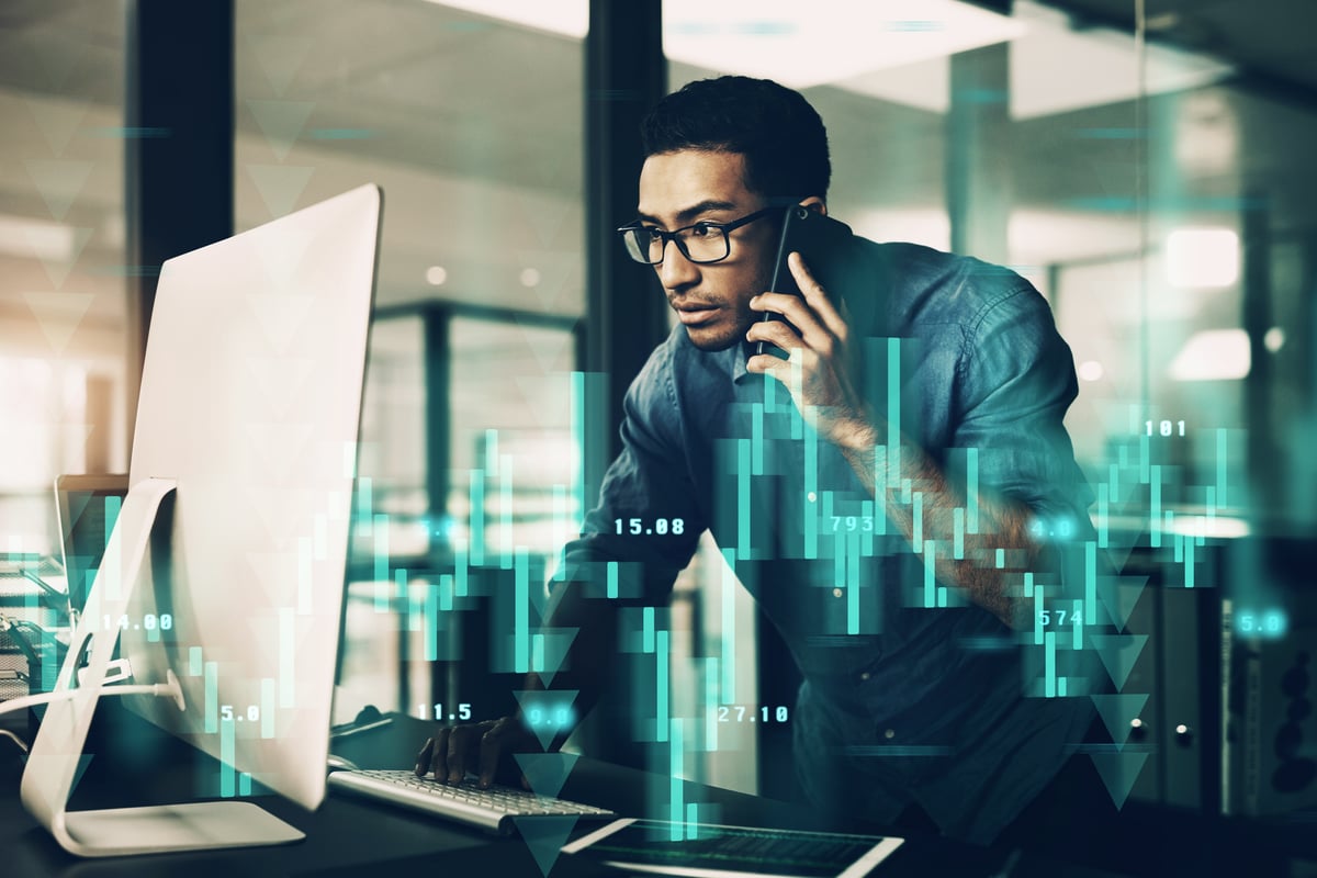 A person on the phone looking at a computer monitor with great interest.
