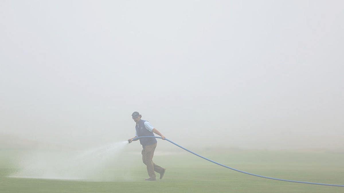 A member of the grounds crew waters the course at Shinnecock Hills Golf Club in Southampton, New York.