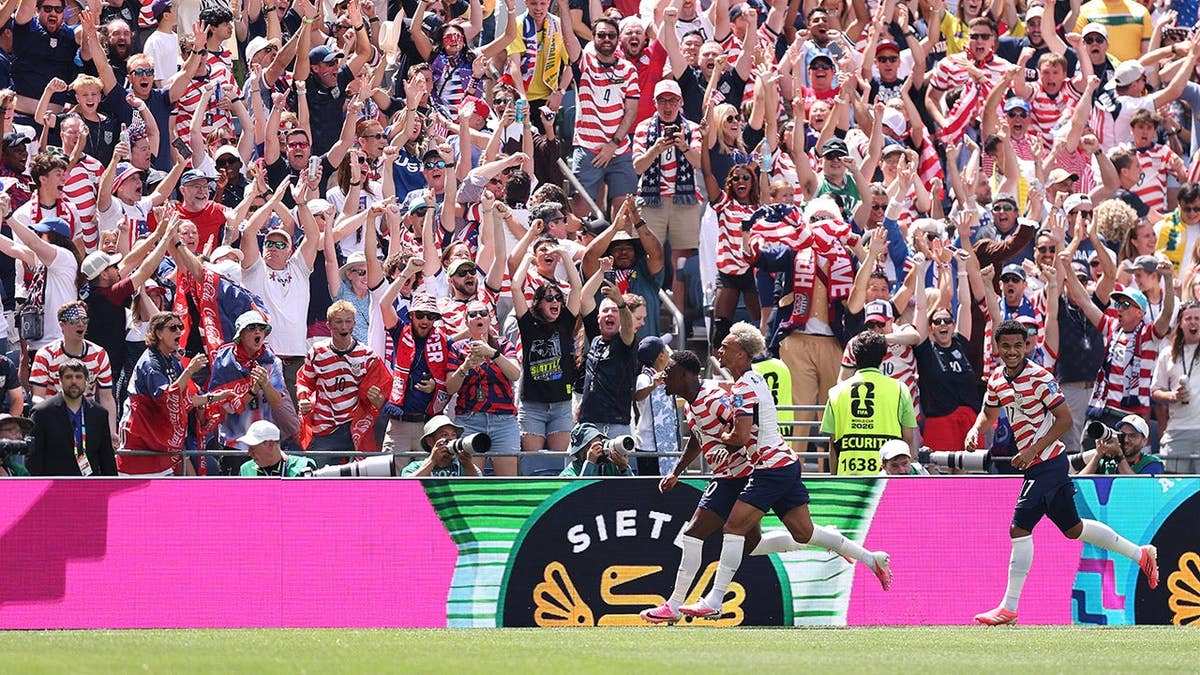 United States soccer players celebrating a goal at Seattle Stadium.