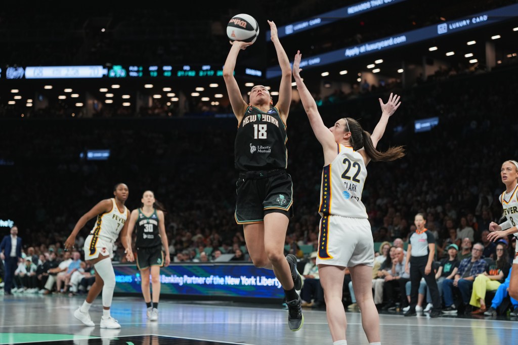 Basketball player Pauline Astier #18 of the New York Liberty shoots a basket over #22 of the Indiana Fever.