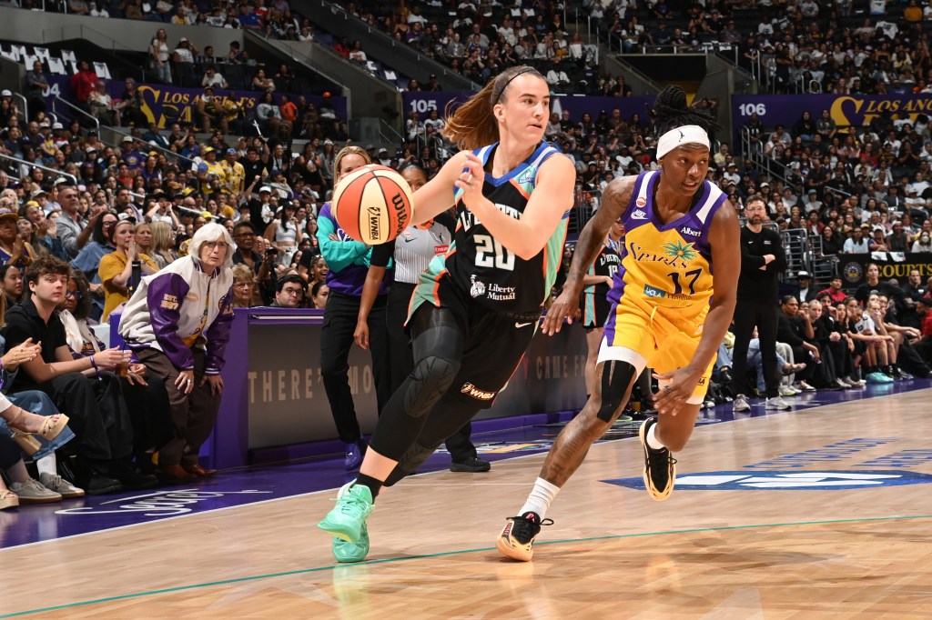 Sabrina Ionescu of the New York Liberty dribbles the ball against a Los Angeles Sparks player during a basketball game.
